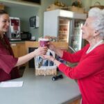 healthcare worker handing a cup of coffee to a senior living resident