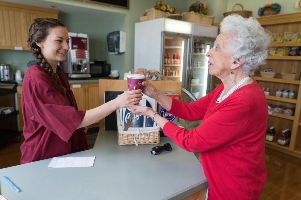 healthcare worker handing a cup of coffee to a senior living resident