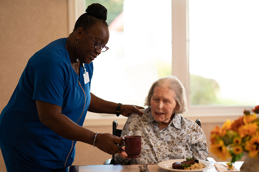 Caregiver serving a female resident coffee