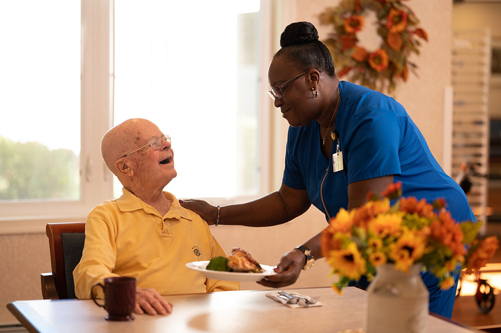 Caregiver serving male resident his lunch