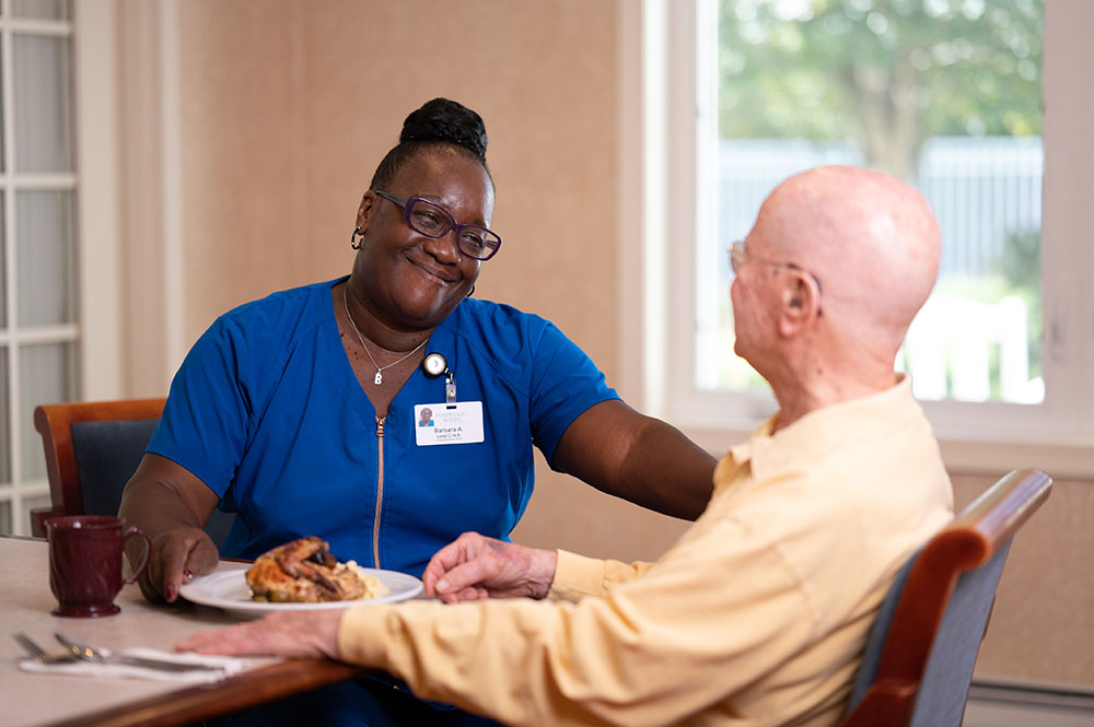 caregiver smiling at male resident at lunch