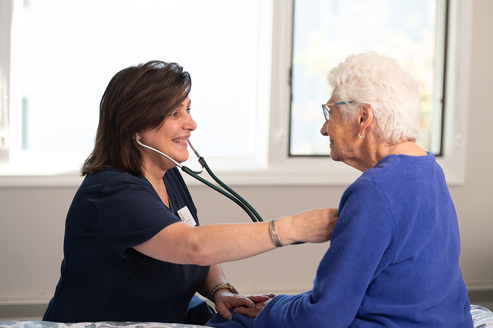 caregiver doing a health check on female resident