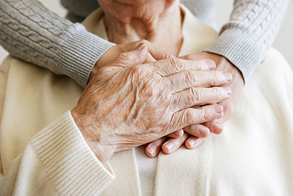 senior holding hands on top of care giver