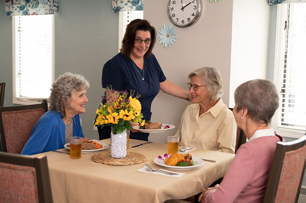 caregiver serving 3 women at lunch table