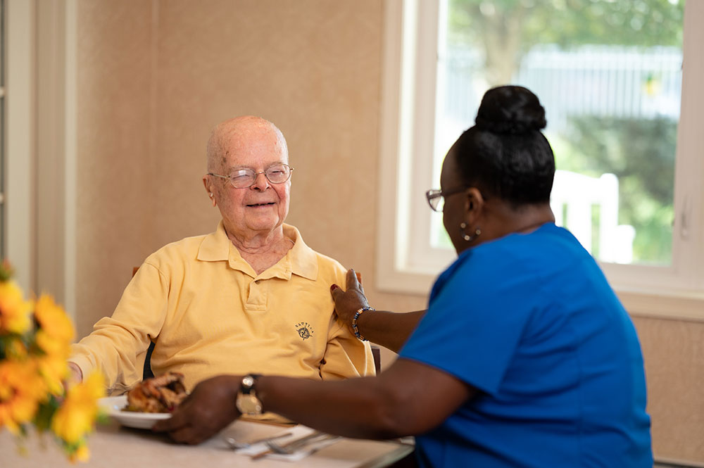 caregiving sitting with male resident at lunch