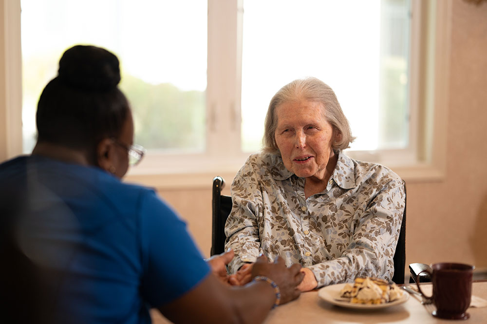 caregiver sitting with resident at lunch