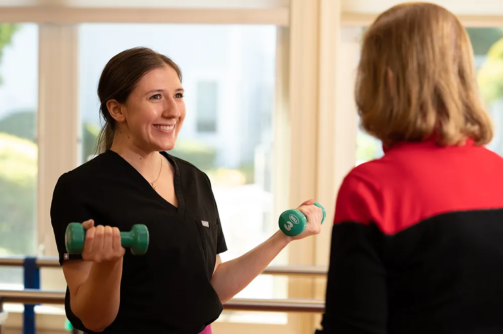 Physical Therapist showing a resident how to properly lift weights